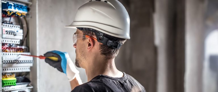 Electricista con equipo de seguridad en un cuadro eléctrico