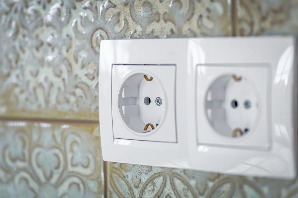 Interruptores y enchufes blancos instalados en la pared
